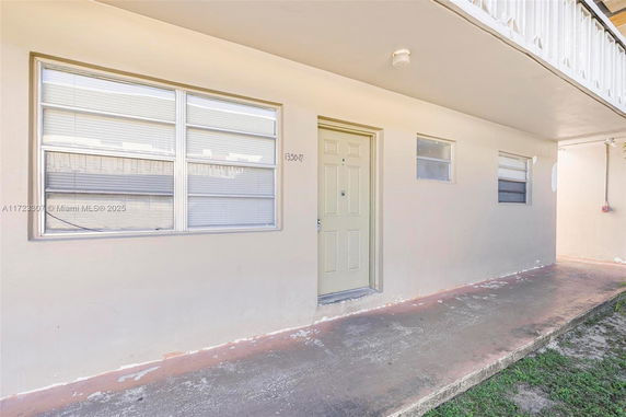 Front view of a simple building entrance with a beige door and windows.