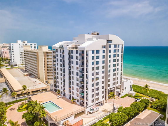 High-rise beachfront condominium building with multiple stories and balconies, overlooks the ocean.