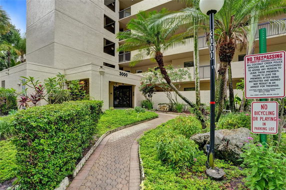Front view of a multi-story building with balconies and landscaped entrance.