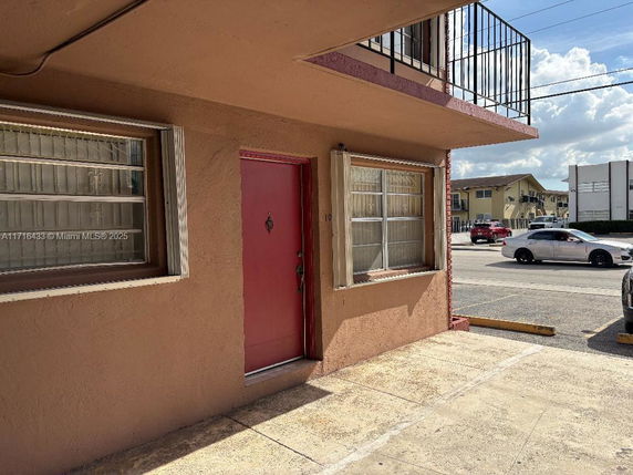 Front view of a building entrance with a red door and windows.