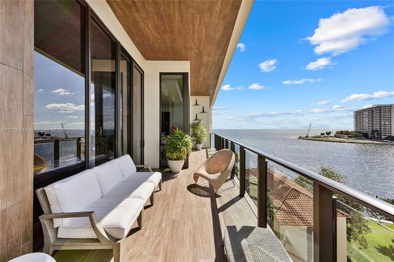 Balcony view overlooking a body of water with distant buildings and a clear blue sky.