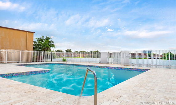 Outdoor swimming pool with fence and surrounding pavement.