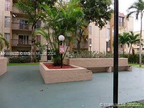 Outdoor recreational area with benches and trees, adjacent to a multi-story building.