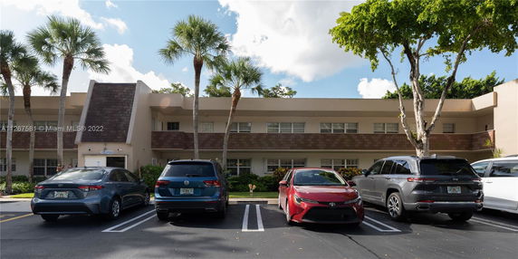 Front view of a two-story building with several cars parked in front.