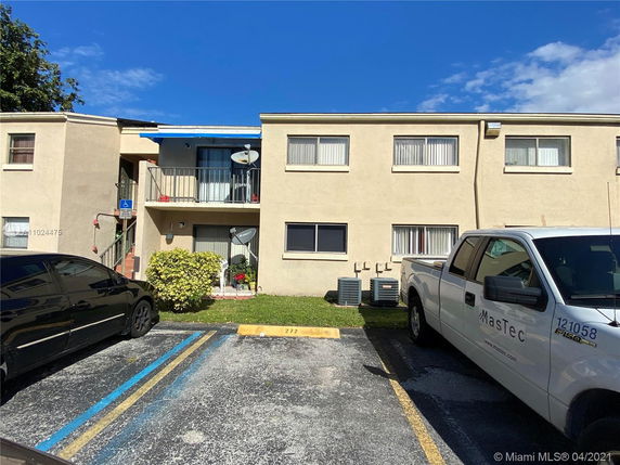 Front view of a two-story apartment building with parking spaces in front.