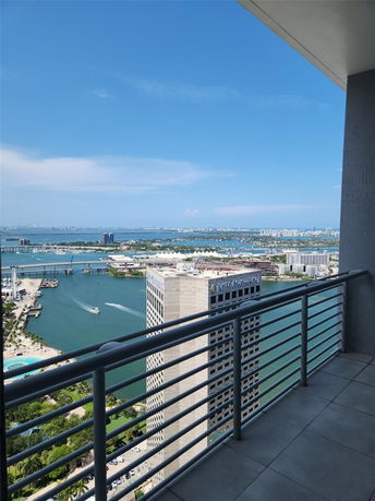 Balcony view from a high-rise building overlooking the ocean and cityscape.