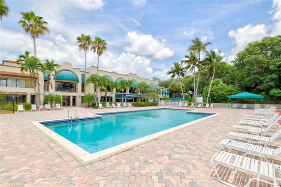 Outdoor swimming pool with adjacent building and palm trees