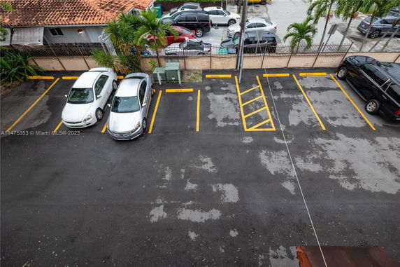 Outdoor parking area with marked parking spaces and several cars parked.