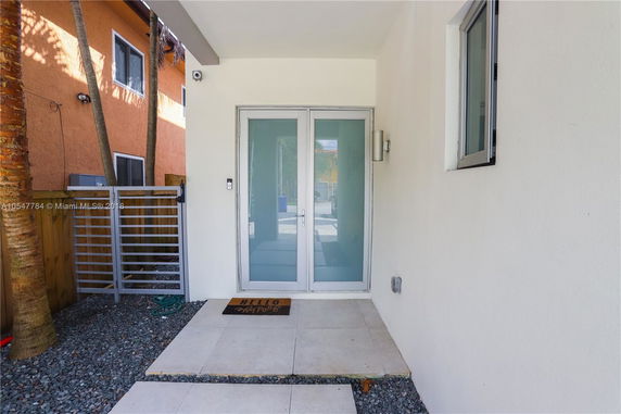 Front view of a modern entrance with a frosted glass door and a small patio.