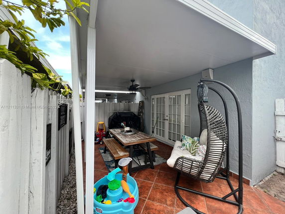 Covered outdoor patio area with seating and a table.
