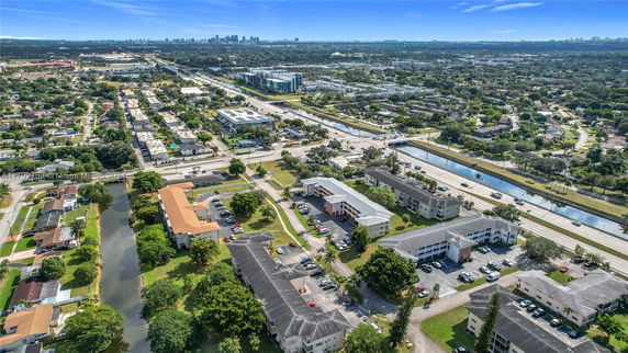 Aerial view of a suburban area with multiple residential buildings, roads, and green spaces.