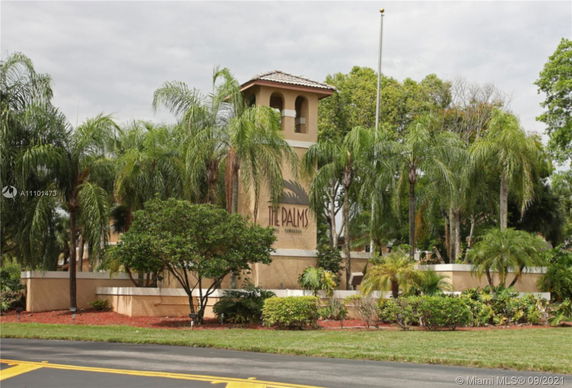 Front view of a building tower with palm trees and a sign reading 'The Palms'.