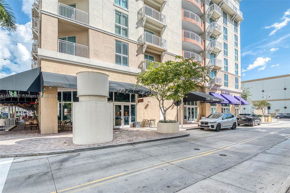 Front view of a multi-story building with balconies and commercial spaces on the ground floor.