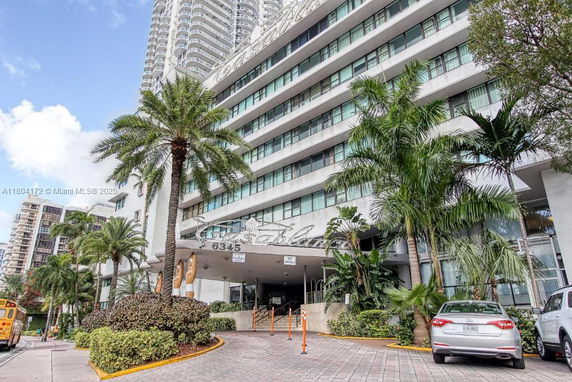 Front view of a multi-story building with palm trees and a driveway.