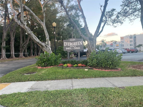 View of a residential sign with buildings and parking lot in the background.