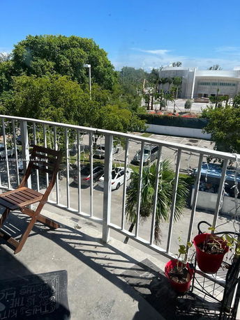 View from a balcony showing a parking area with cars and lush green trees.