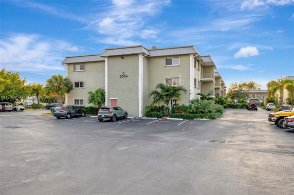 Front view of a three-story residential building with a parking area.