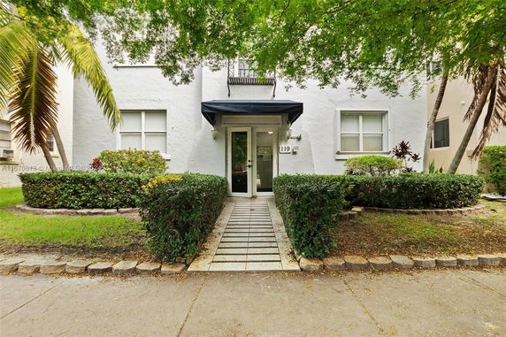 Front view of a building entrance with a pathway and shrubs.