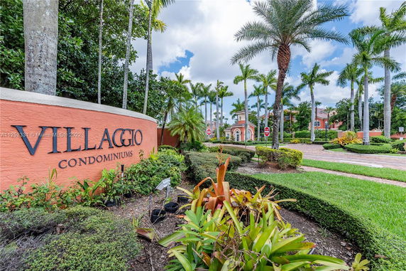 Exterior view of Villaggio Condominiums with landscaped entrance and palm trees.