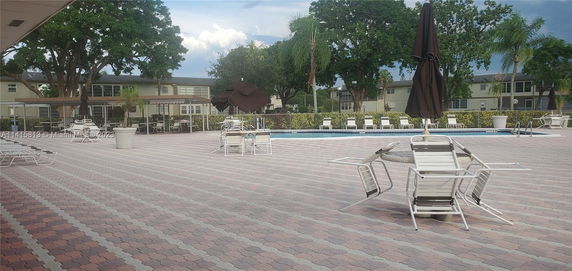 Outdoor swimming pool area with lounge chairs and umbrellas.