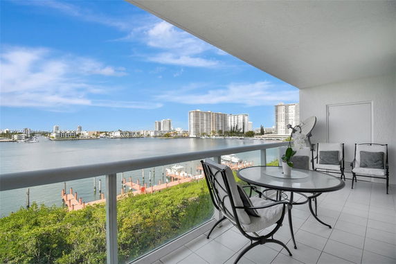 Wide angle view of a balcony overlooking a waterway with high-rise buildings in the background.
