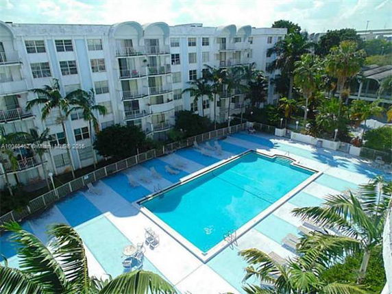 View of a large outdoor swimming pool surrounded by a multi-story residential building.