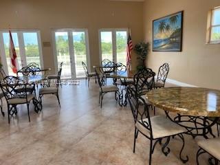 Room with multiple tables and chairs, decorated with a painting and flags.