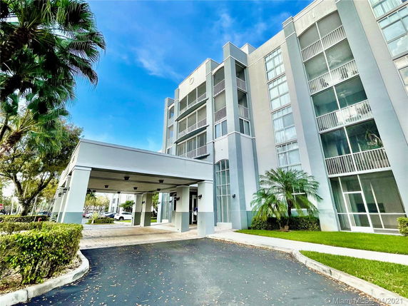 Front view of a multi-story residential building with balconies and a covered entrance.