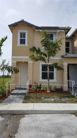 Front view of a two-story house with a tan exterior and white trim.
