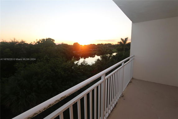 View from a balcony overlooking a sunset and lush greenery.