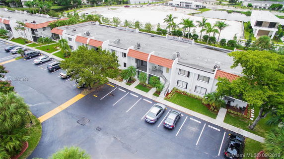 Aerial view of a multi-story residential building with adjacent parking spaces.