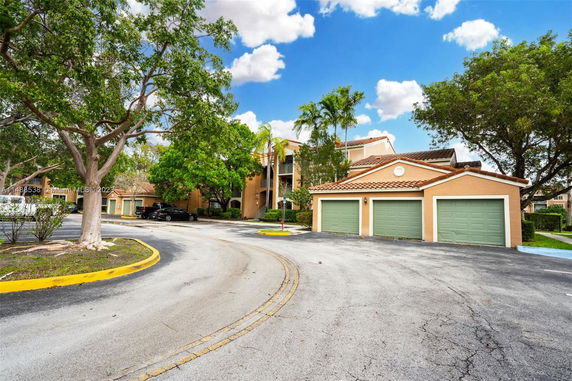 Front view of a multi-story building with attached garages and a driveway.