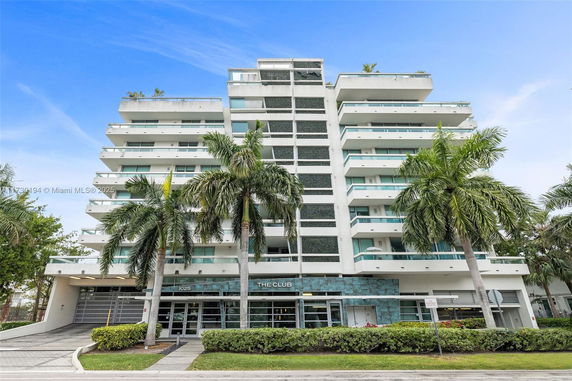 Front view of a multi-story building with balconies and palm trees.