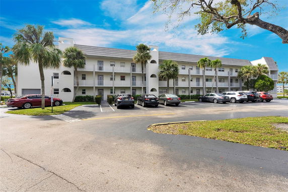 Front view of a multi-story residential building with a parking area in front.