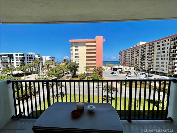 View from balcony showing multiple apartment buildings and ocean in the distance.