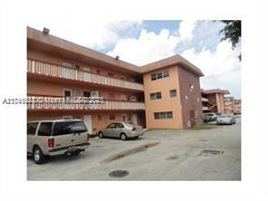 Front view of a multi-story apartment building with outdoor parking.