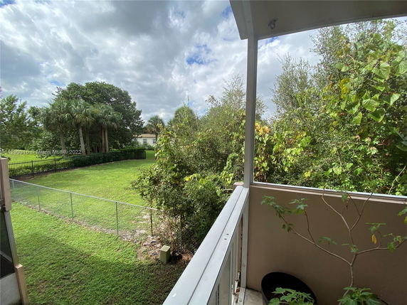 View of a grassy backyard and trees from a balcony.