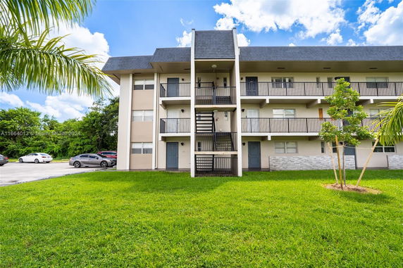 Front view of a multi-story apartment building with balconies and central staircase.