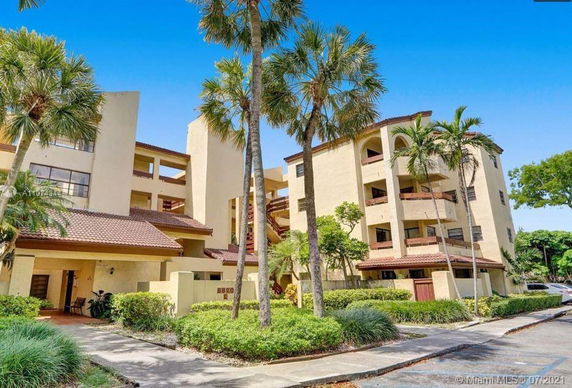 Front view of a multi-story residential building with balconies and landscaped surroundings.