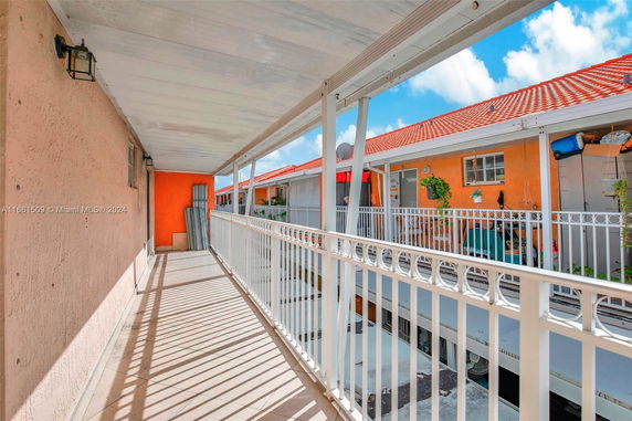 View of an outdoor walkway with railings, orange walls, and a tiled roof.