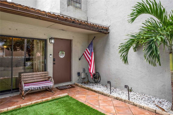 Front view of a house entrance with a bench and an American flag.
