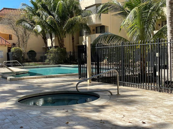Outdoor swimming pool area with a jacuzzi and surrounding palm trees.