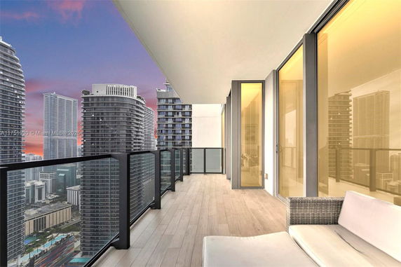 Balcony view overlooking a cityscape with tall buildings at sunset.