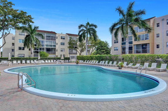 Outdoor swimming pool area surrounded by multi-story residential buildings.
