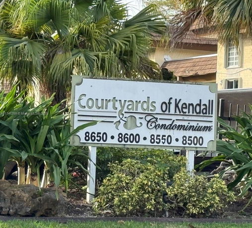 Sign for Courtyards of Kendall Condominium with building in background.