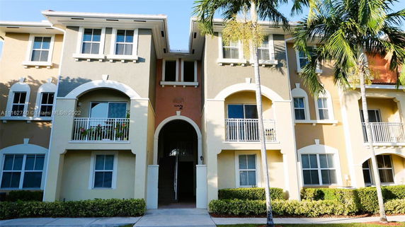 Front view of a multi-story residential building with balconies and decorative arches.