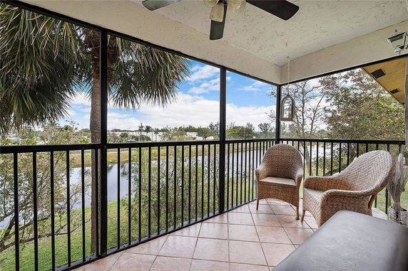 Balcony view with chairs and railings overlooking a scenic landscape with trees and water.