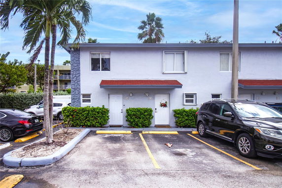 Front view of a two-story building with adjacent parking spaces.