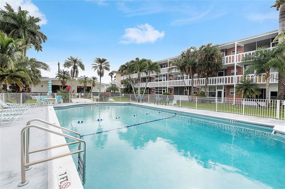 Outdoor swimming pool in front of a residential building with multiple floors.