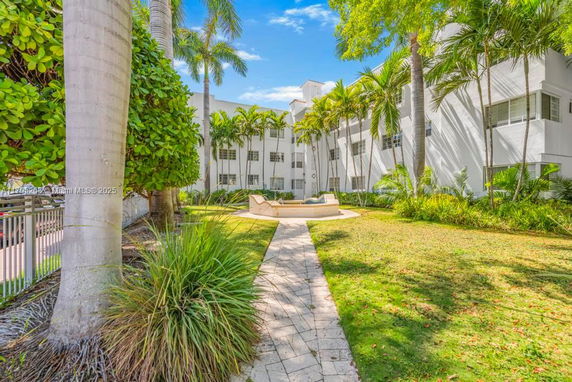 Front view of a multi-story building with a landscaped garden and palm trees.